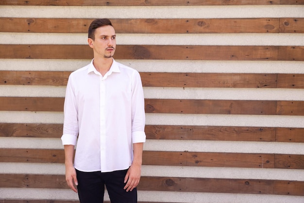 Sad bearded European man in a white shirt looking away on a brown ribbed background with copy space