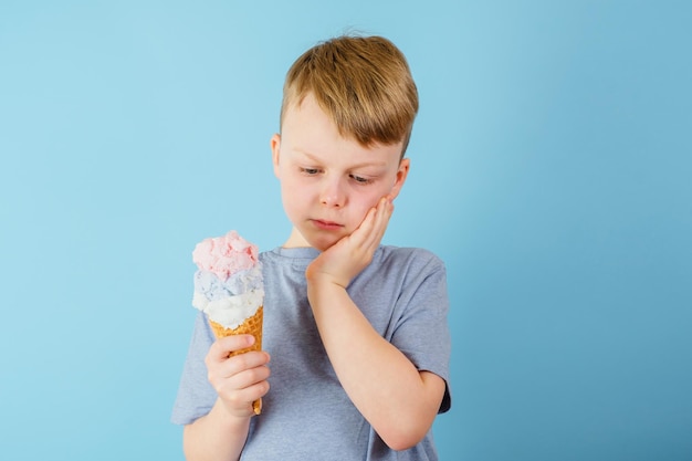 Sad boy grabbed his cheek felt a sharp toothache The child holding ice cream in his hand