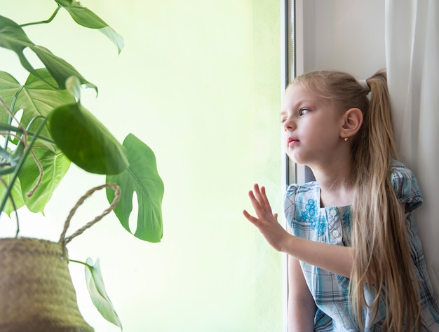 Sad child girl by the window