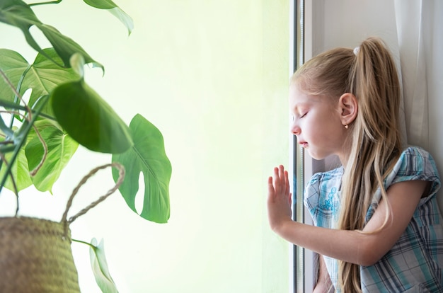 Sad child girl by the window