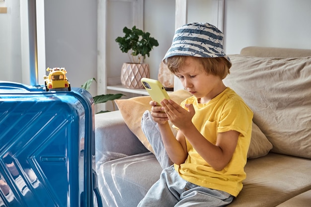 A sad child is sitting on a sofa using a mobile phone and waiting for departure family relocation fl