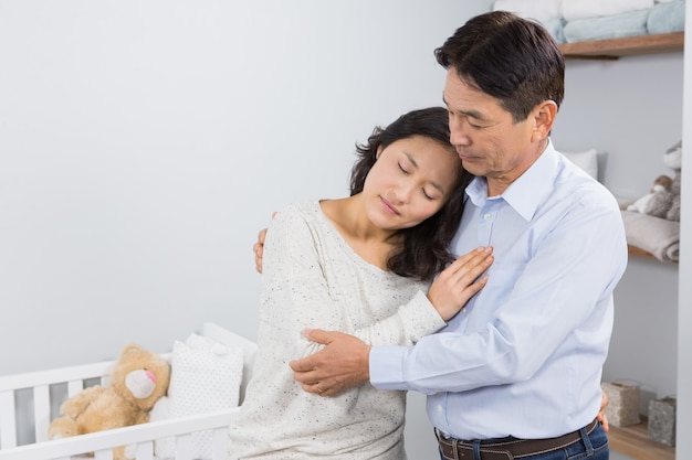 Sad couple embracing at home against crib