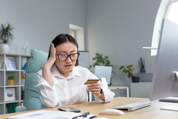 Sad and disappointed asian woman trying to make a purchase in online store business woman using phon