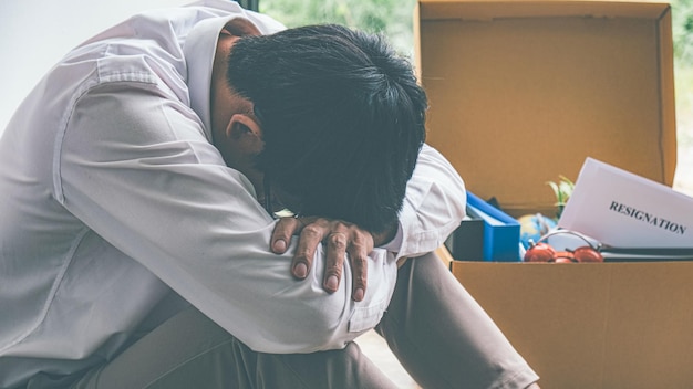 Sad dismissed businessman sitting outside the office after losing his job