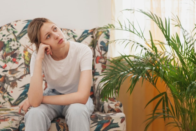 Sad emotion young woman is sit in waiting room wait for her turn. Female sitting on sofa feels apathy uncomfortable