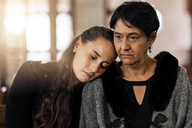 Sad empathy and funeral with women in church for mourning grief and death Loss respect and console with mother and daughter at chapel for burial ceremony for depression remember and sorrow