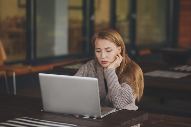 Sad girl in a cafe looking into a tablet