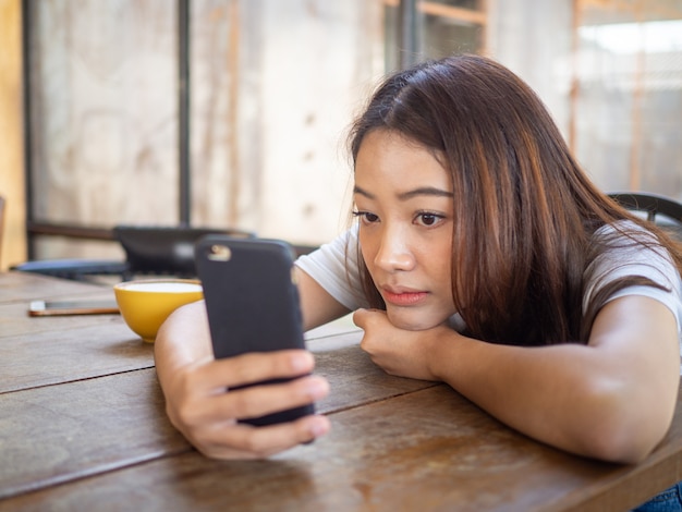 The sad girl is waiting for a phone call or text message from her boyfriend. Sitting lonely and anxious in a coffee shop