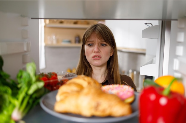 Sad girl looks into the fridge