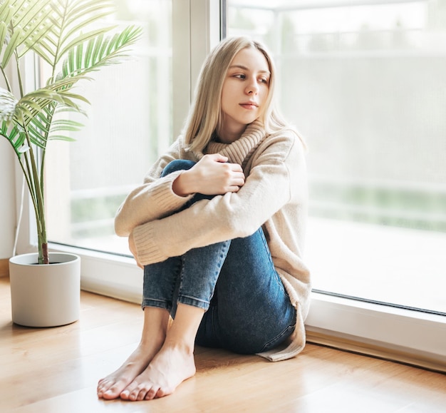 Sad girl near window thinking about somethingxA