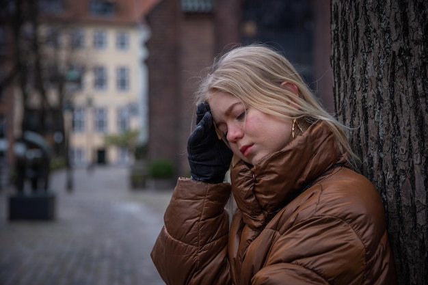 Sad girl with hands on forehead and look down mental health concept copy space on the left