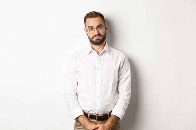 Sad and gloomy office manage frowning, standing tired against white background.