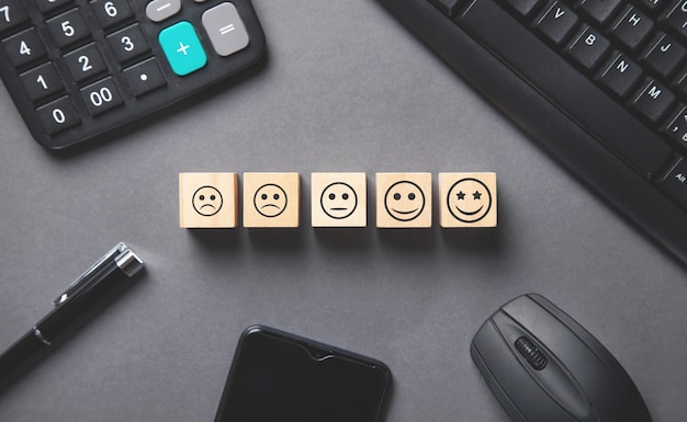 Sad and happy smileys on wooden cubes with a business objects. Customer satisfaction