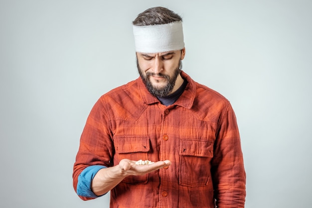 Photo sad injured bandaged man with pills