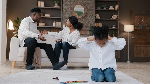 Sad little african daughter child kid girl closing ears upset at parents fighting arguing conflict