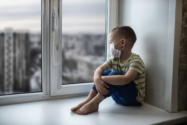 Sad little boy with protective mask during the isolation