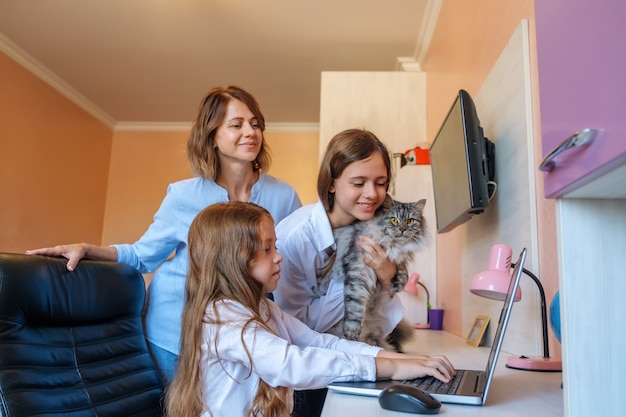 Sad little girl does homework and is helped by her mom and sister