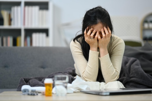 Sad lonely young woman having psychological trouble sitting in living room with prescription pill bottles Mental heath concept