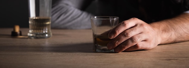 Sad man hand glass of whiskey