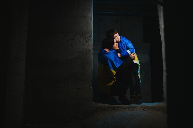 Sad mother hugging her son both wearing Ukrainian national colors on black background