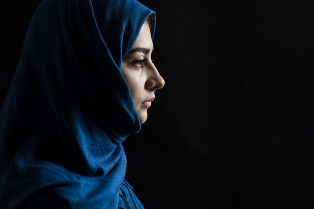 Sad Muslim girl on a black background. 