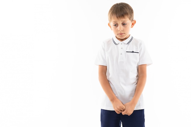 Sad offended boy with bangs in a white t-shirt on white with copy space