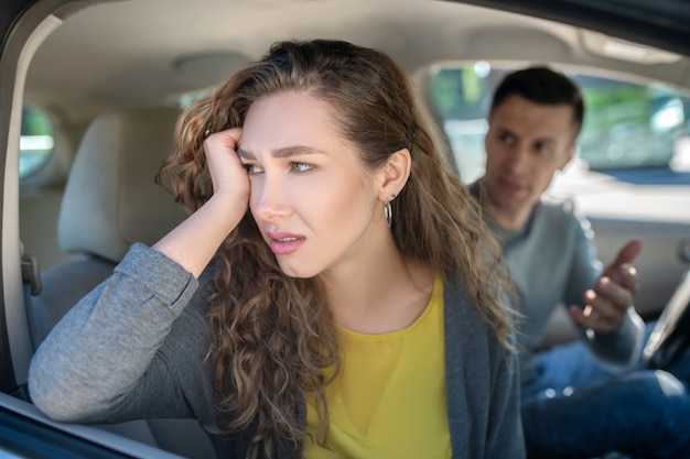 Sad pensive woman and misunderstanding man in car