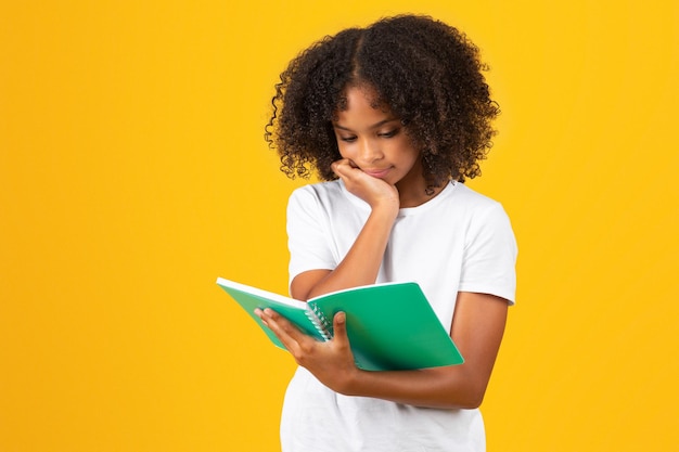 Sad serious smart adolescent african american girl in white tshirt reading book