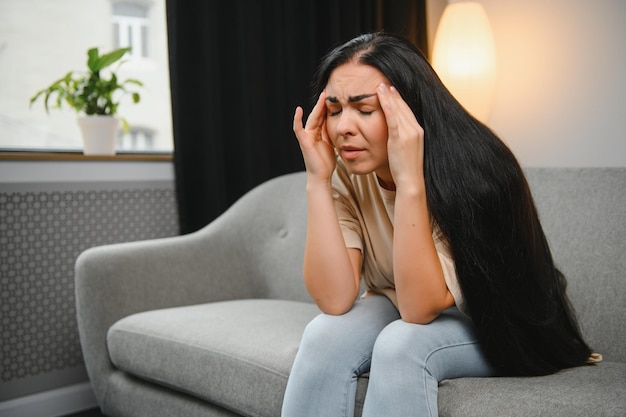 Sad tired young woman touching forehead having headache migraine or depression upset frustrated girl troubled with problem feel stressed cover crying face with hand suffer from grief sorrow concept