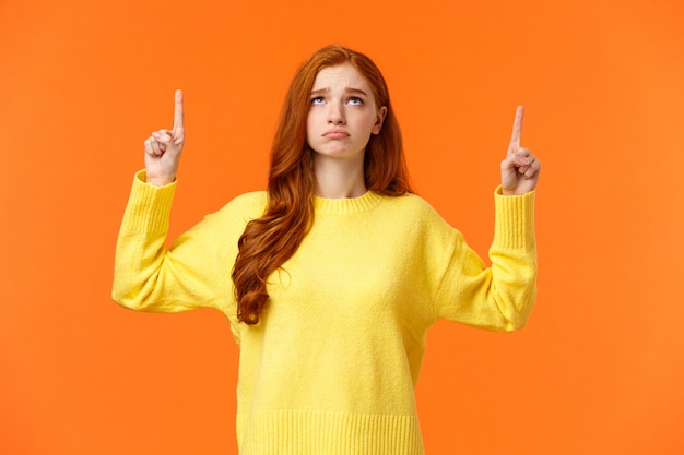 Sad and unhappy sulking redhead woman in yellow sweater, unsatisfied, look gloomy on Christmas holidays