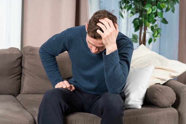 Sad upset depressed unhealthy guy young tired exhausted frustrated man is suffering holding his head