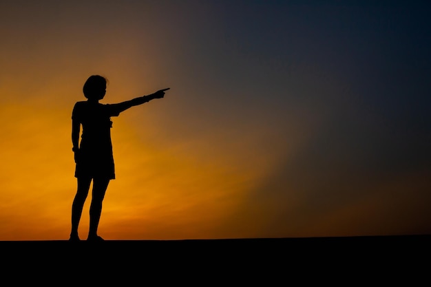 Sad woman alone pointing at sunset on the park