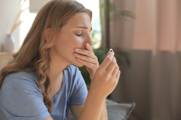 Sad woman sitting on a sofa in the living room.