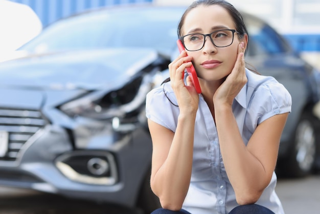 Sad woman talking on phone after broken car reporting an accident concept