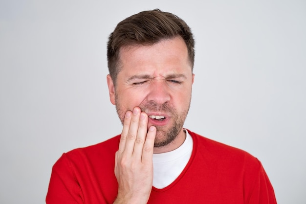 Sad young man having a toothache isolated over white background