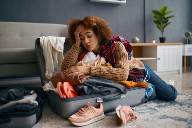 Sad young woman and unpacked vacation luggage