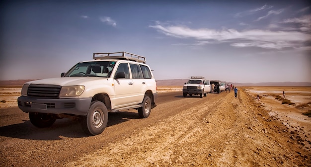 Safari and travel to Africa-extreme adventures in Sahara desert. Jeep breakdown in scorching sun in middle of salt marsh, deserted road and off-road vehicles