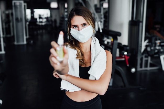 Safe sport, personal trainer in a protective mask in the middle of a modern hall.