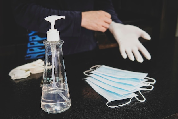 Safety equipment to fight to Coronavirus COVID-19 virus outbreak - Safety mask, hand sanitizer, latex gloves. man puts on white rubber gloves to clean the apartment