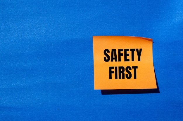 Photo safety first message written on orange paper with blue background conceptual safety first symbol copy space