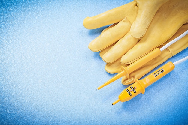 Safety gloves electric tester on blue background electricity concept.