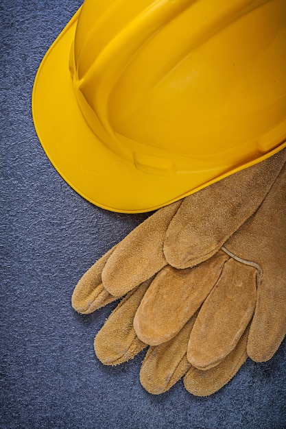 Safety hard hat leather gloves on black background construction concept