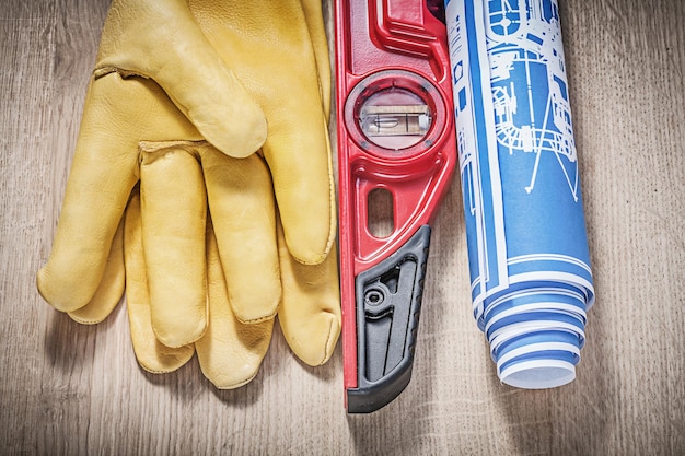 Safety leather gloves construction level blueprints on wooden board