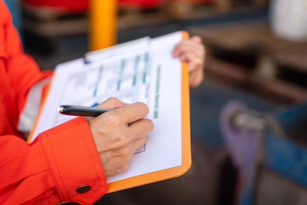 A safety officer is checking on the hazardous material checklist form with chemical storage area at