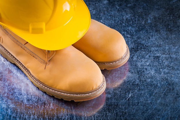 Safety working boots and building helmet on scratched metallic surface construction concept