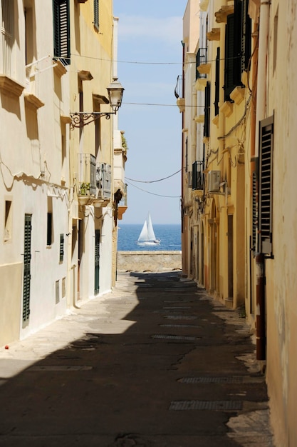 Sailboat is seen on the sea between two Gallipoli buildings Gallipoli Province of Lecce Apulia Italy