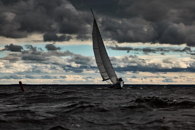 Sailboat in sea at stormy weather stormy clouds sky sail regatta big waves of water