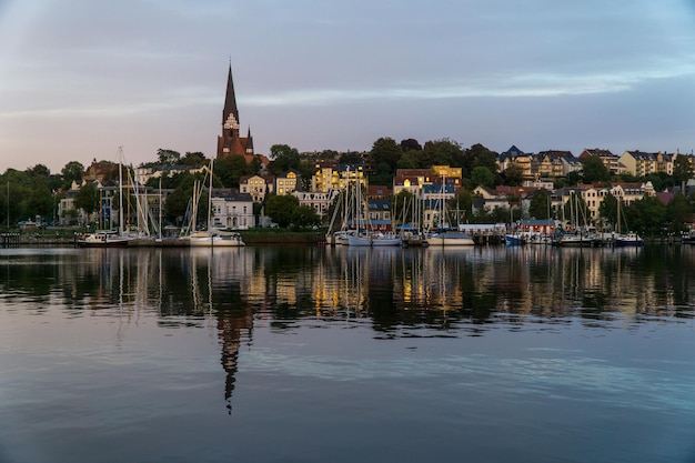 Sailboats in river by buildings against sky in city