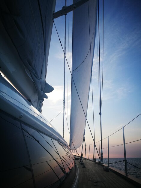 Sailboats sailing on sea against sky during sunset