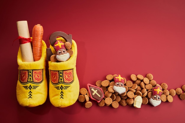 Saint nicholas  sinterklaas day with shoe carrot and traditional sweets on red background